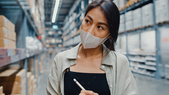 Young Asia businesswoman manager wear face mask  using digital tablet checking inventory. - Stock Photo - Images