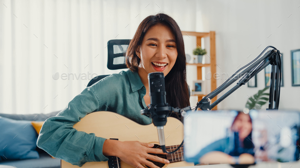 Asia girl influencer play guitar music record with smartphone for online audience listen at home.