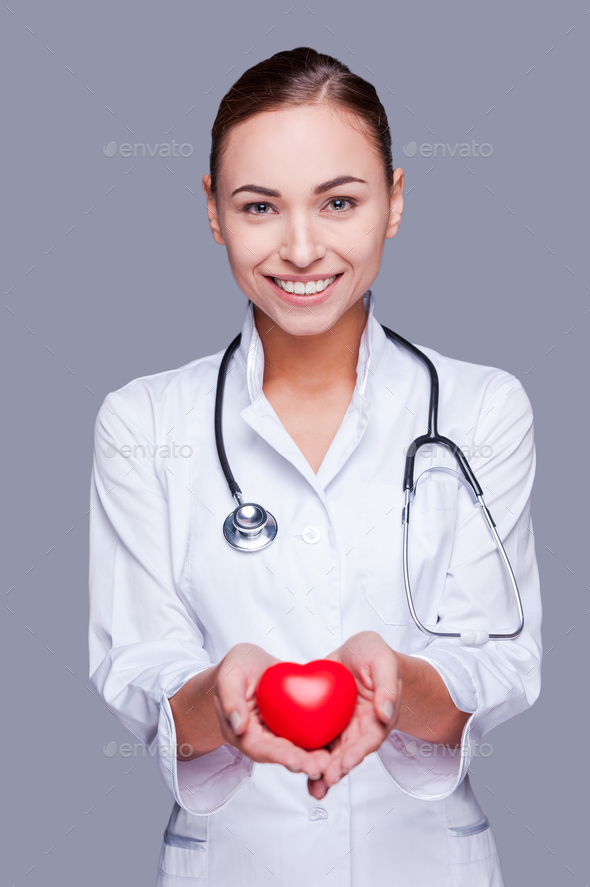 Your heart in good hands. Confident female doctor in white uniform ...