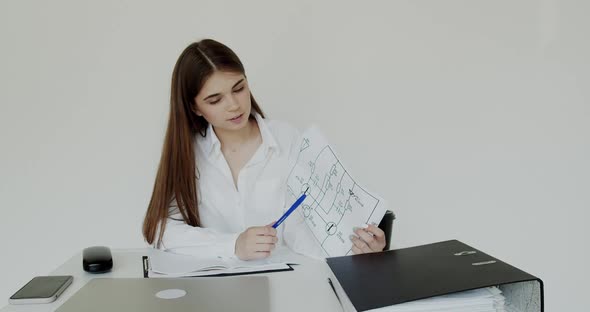 Happy Girl Talking and Showing Printouts at Camera at Workplace alt