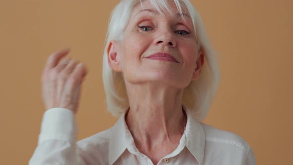 Positive mature woman correcting her appearance at camera alt