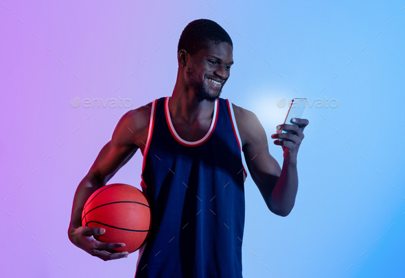 Positive black basketball fan watching championship online, cheering for his favorite team on