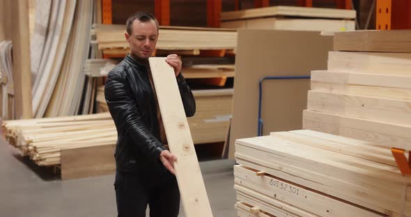 Man Chooses Wooden Desk in a Building Market