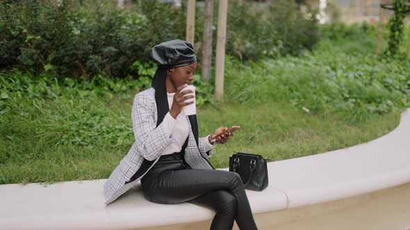 Muslim Female Drinking Coffee and Using Cellphone on Border alt