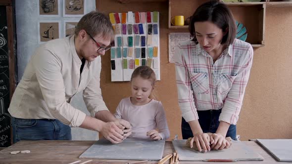 Little Girl with Her Adult Mother and Father Working with Clay