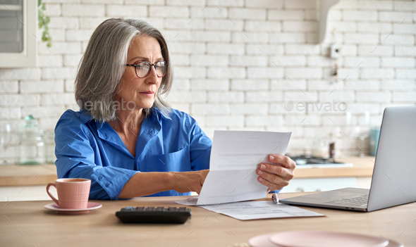 Senior mid 60s aged woman calculating bank fee with computer. - Stock Photo - Images