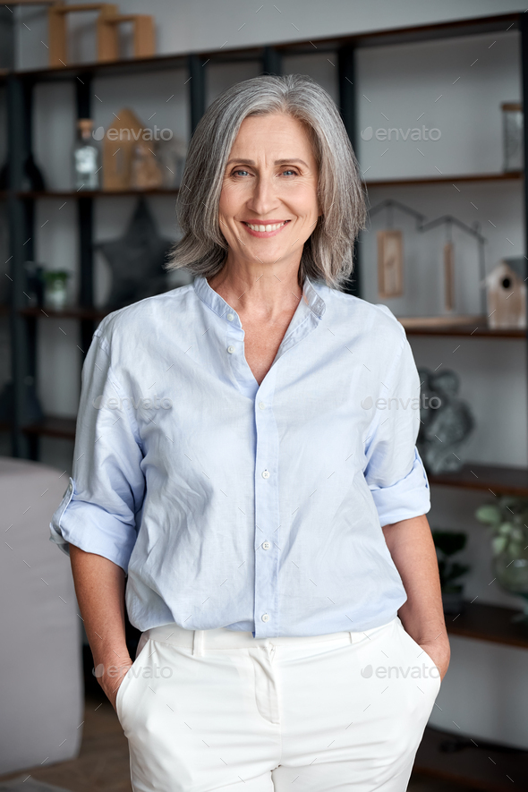 Smiling elegant confident middle aged woman standing in office