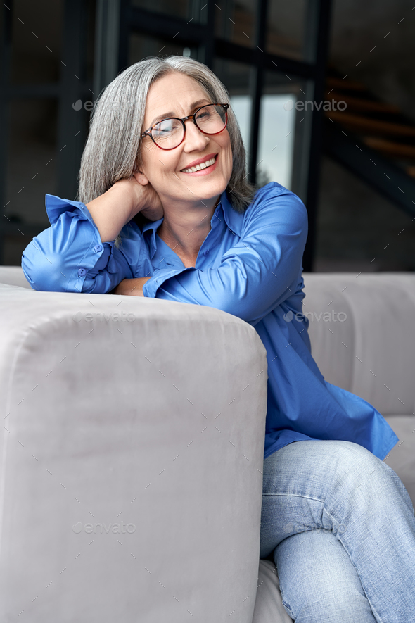 Happy relaxed mature old woman wears glasses sitting on couch at home ...