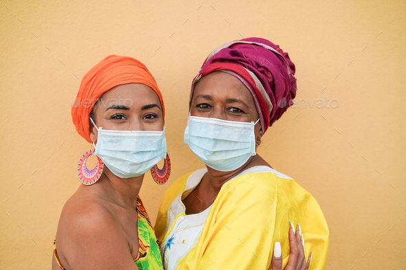 African mother and daughter hug each other while wearing surgical face mask - Family love