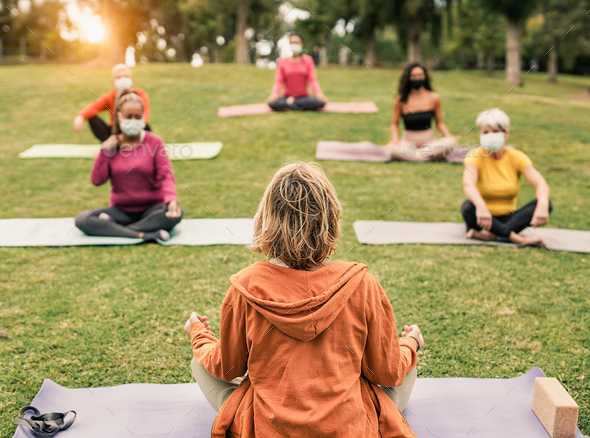 Yoga teacher doing exercise at nature park with multiracial women