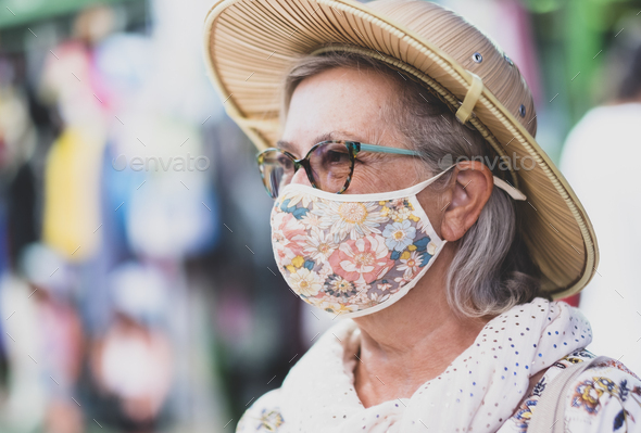Side view of a smiling senior woman with glasses and scarf wearing a medical mask due to coronavirus
