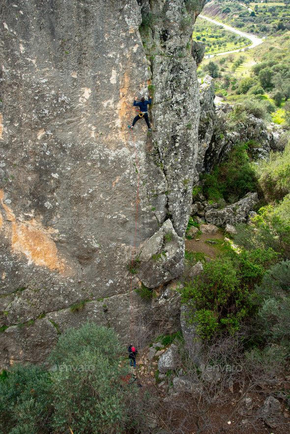 Unrecognized person climbing to the top of a Rock. Outdoor activities healthy lifestyle