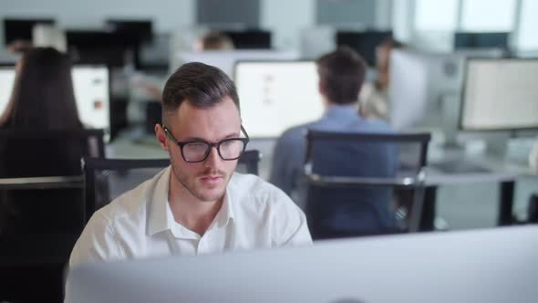 Portrait of Young Entrepreneur in Open Space Office Working on Decktop Computer alt