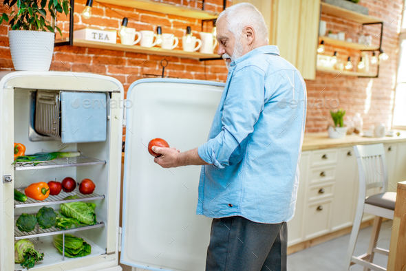 Senior man with healthy products in refrigerator