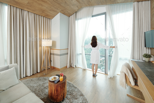 Woman opening curtains - Stock Photo - Images