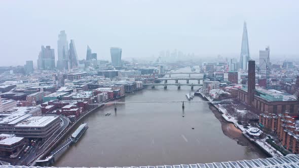London snow aerial dolly forward drone shot towards iconic city centre and river thames alt