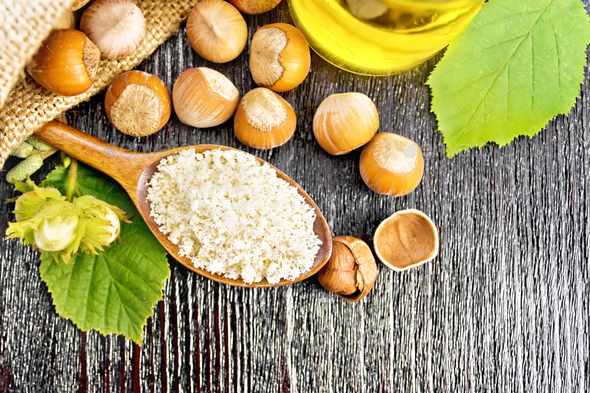 Flour in spoon with nuts on board top - Stock Photo - Images