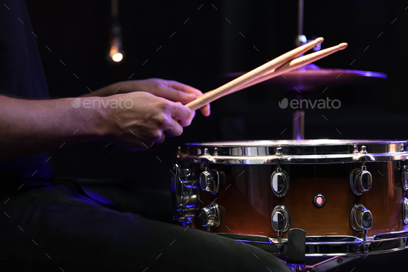 Drummer playing snare drum with sticks close up.