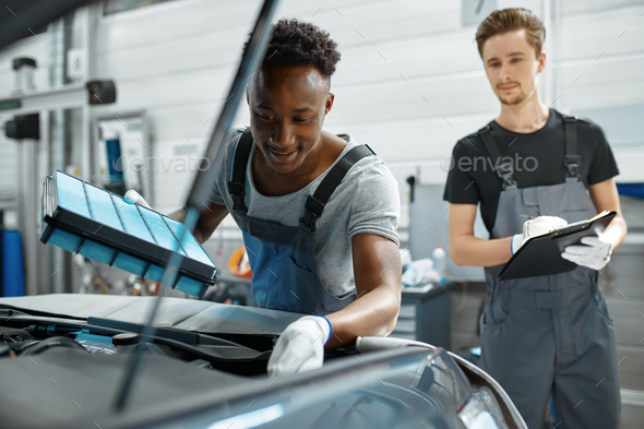 Two male workers repairs engine, car service - Stock Photo - Images