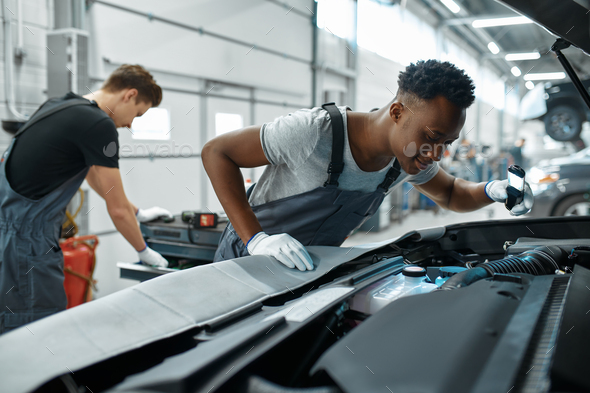 Two male mechanics inspects engine, car service - Stock Photo - Images