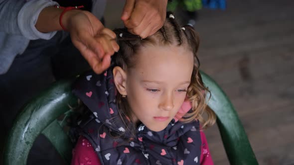 Female Hair Stylist Braiding Hair of Little Girl alt