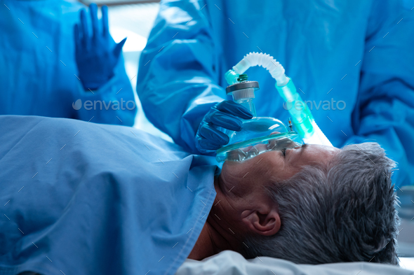 Caucasian female patient lying on surgical bed with oxygen mask