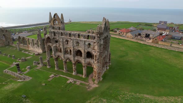 Drone orbiting around Whitby Abbey ruins with sea and city in background, North Yorkshire in England alt