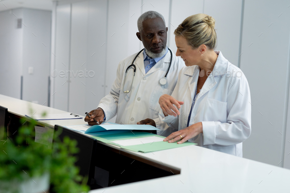 Diverse male and female doctors standing in hospital corridor looking at medical documentation