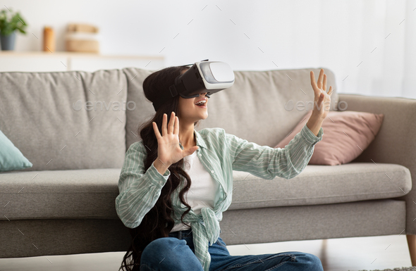Millennial Indian woman in virtual reality glasses exploring cyberspace, playing interactive video