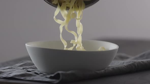 Slow Motion Put Fettuccine Into White Bowl on Linen Cloth alt