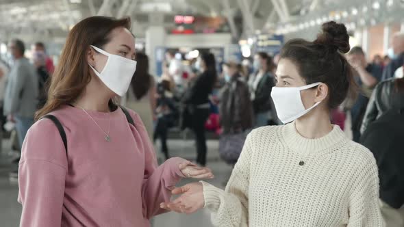 Two Women in Medical Mask Portrait Laughing and Emotionally Talking in Airport Terminal Preventing alt
