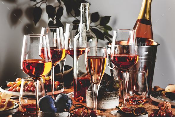 Rose wine glasses and bottles on table served for festive dinner party  Stock Photo by Olga_Kochina