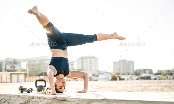 Portrait of athletic woman exercising calisthenic balance move at outdoors beach location