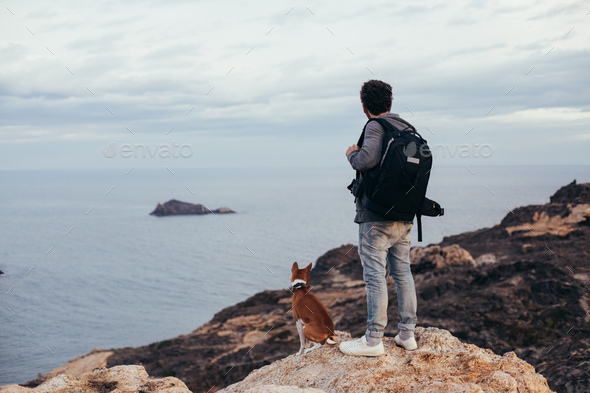 Traveler adventurer man with dog on mountain