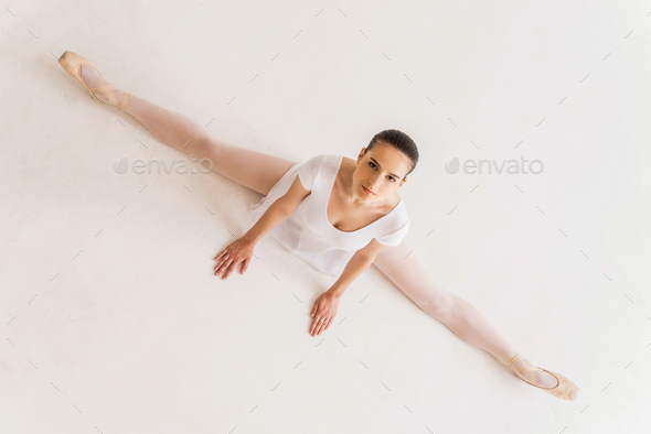 It takes discipline to be the best. Top view of young ballerina in white tutu doing splits