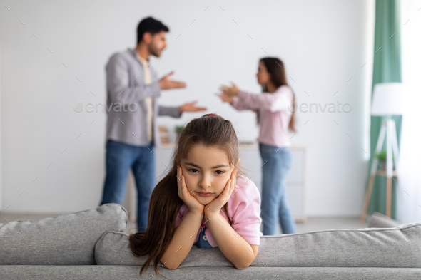 Family crisis and relationship problems. Upset girl looking at camera while her angry parents