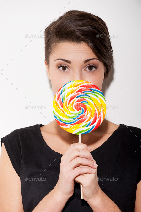 Really big lollipop. Surprised young short hair woman holding a big