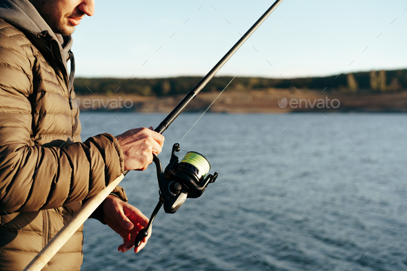 Fisherman hands holding fishing rod close up Stock Photo by