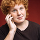 Portrait of smiling curly red-haired freckled teenager with telephone on red background - PhotoDune Item for Sale