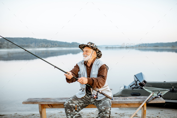 Senior man fishing on the lake Stock Photo by RossHelen