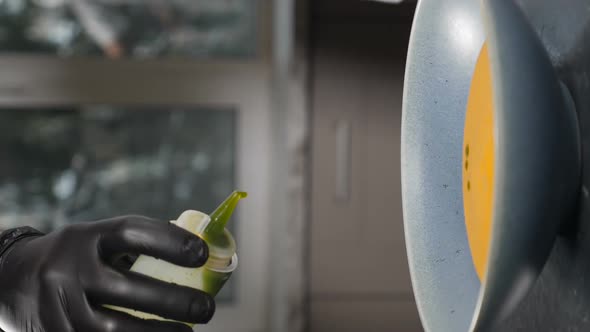 Chef Serving Pumpking Soup in Restaurant Kitchen Dropping Oil As Finish Touch alt