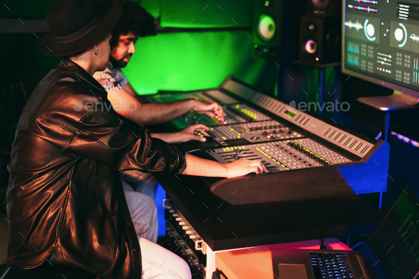 Music producers mixing new record album inside production studio room - Soft focus on woman