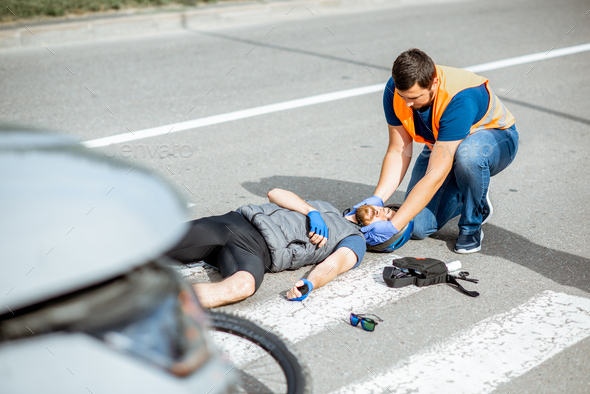 Road Accident With Injured Cyclist And Man Providing First Aid Stock 