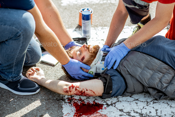 Medics applying emergency care to the injured man on the road - Stock Photo - Images