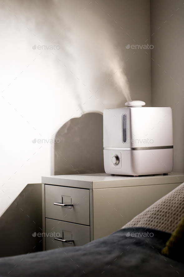 Aroma oil diffuser/humidifier on bedside table at night Stock Photo by