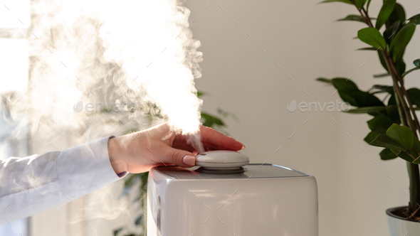 Woman turn on and inhaling aroma oil steam from humidifier