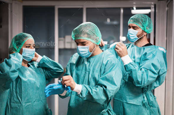 Doctors and nurse preparing to work in hospital for surgical operation during coronavirus outbreak - Stock Photo - Images
