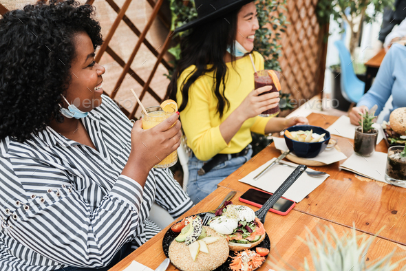 Multiracial young women eating brunch during coronavirus outbreak - Stock Photo - Images