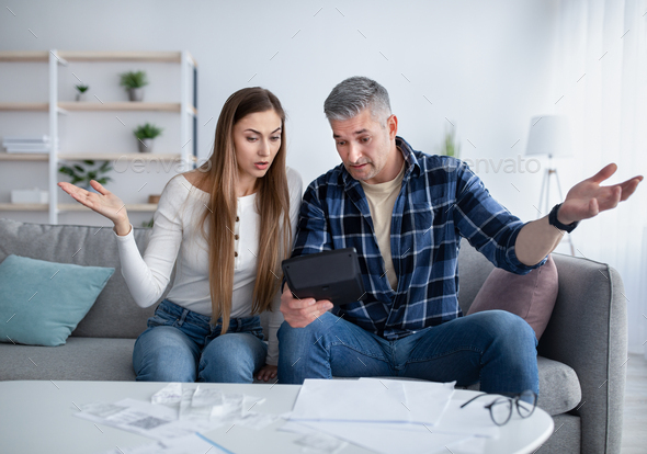 Financial crisis. Unhappy married couple calculating bills and expenses, unable to pay debts at home