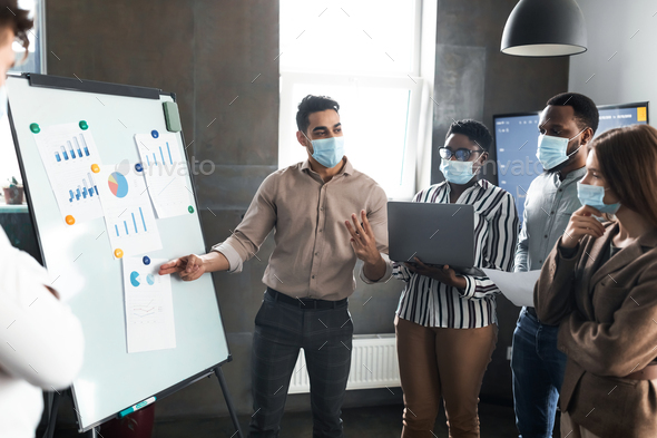 Employee in protective face mask presenting business strategy on whiteboard